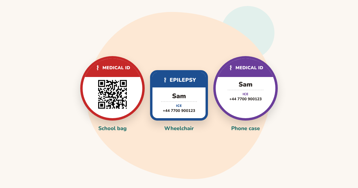 Three medical ID stickers: a round red one with a QR code on a school bag, a square blue EPILEPSY label on a wheelchair, and a round purple label with a name and phone number on a phone case